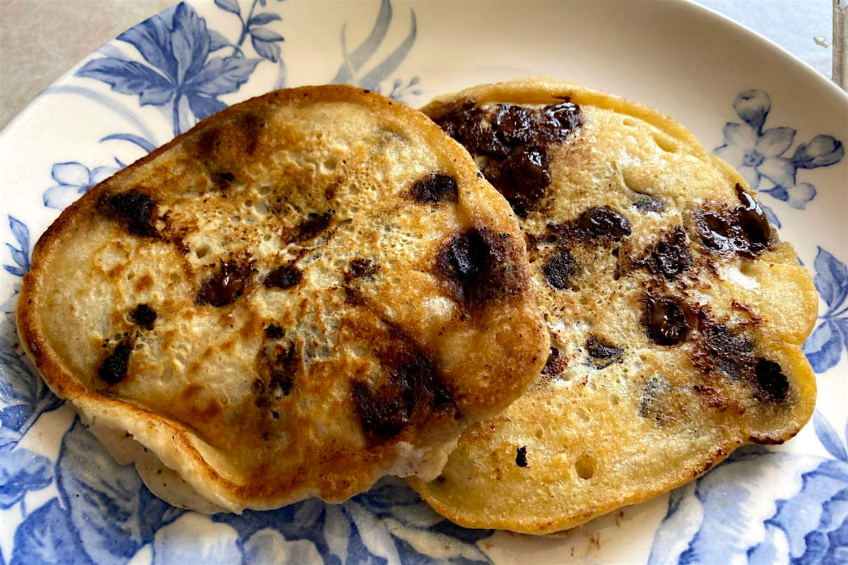 Blue and white floral plate with 2 vegan chocolate chip pancakes on it.