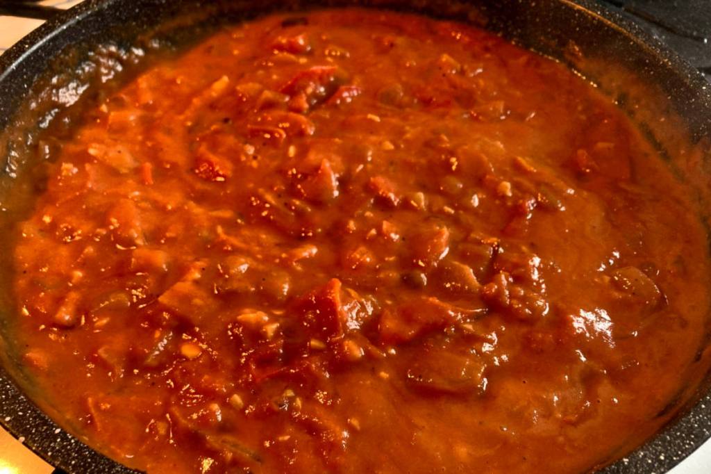 Tomatoes simmering in pan for vegan aloo gobi recipe.