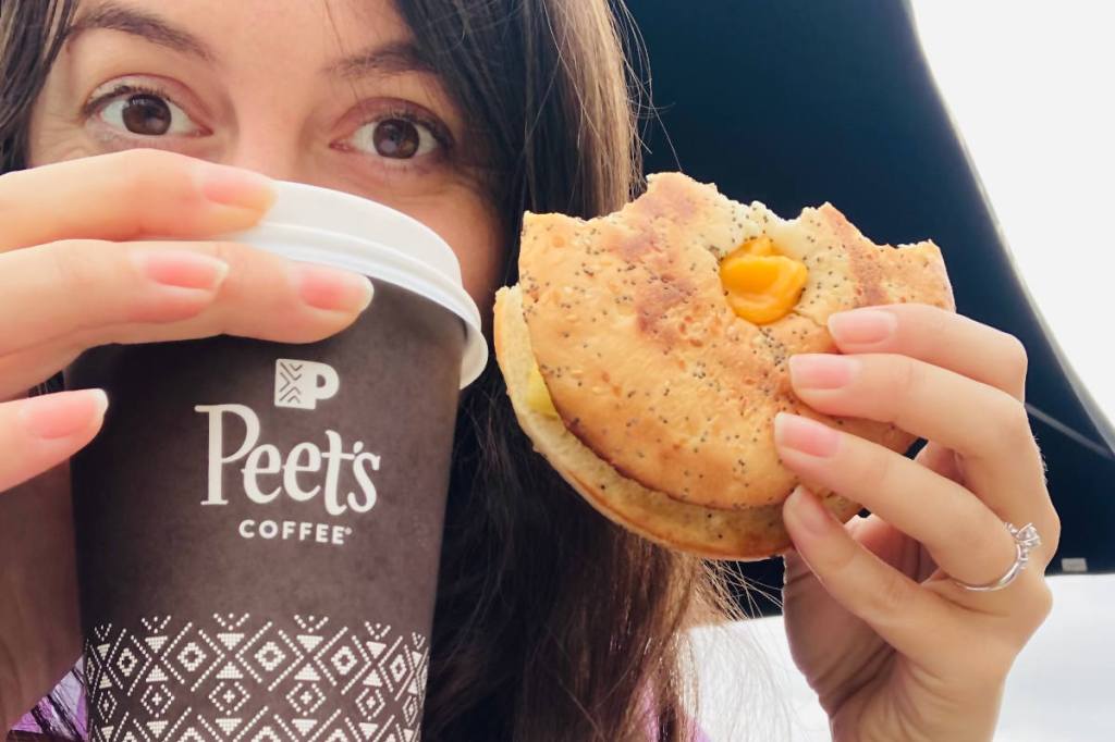 The veggan, Gina, holding Peet's vegan breakfast sandwich and a small vanilla oatmilk latte.