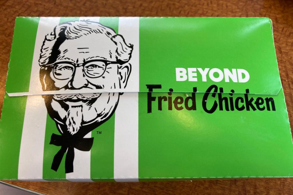 Closed green beyond fried chicken box on the table inside of a kfc restaurant.