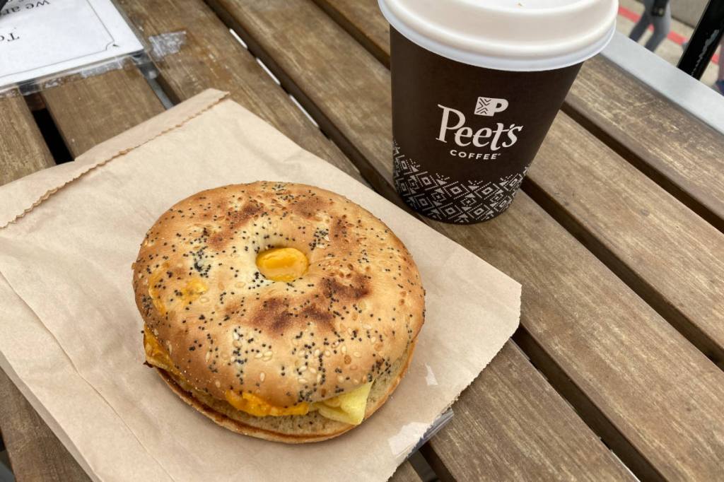 Peet's vegan breakfast sandwich on a wood table with a small oatmilk vanilla latte.